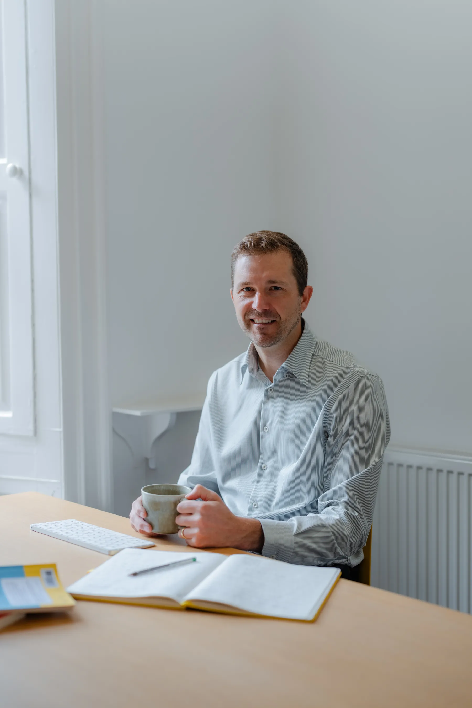 Nat Baldwin seated at a desk in a bright room, smiling