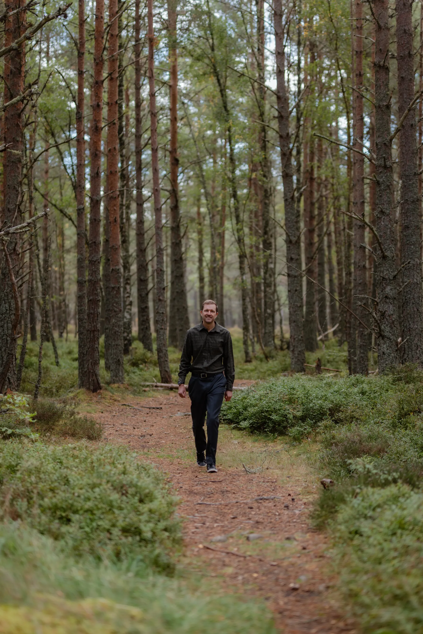 Nat Baldwin walking along a narrow path through a Highland pine forest